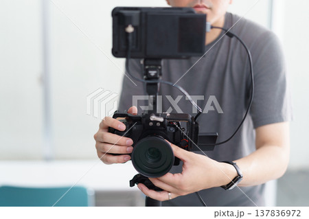 室内でTシャツを着て動画撮影をする男性の上半身 137836972