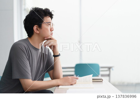 資格を取得する為の講義室で教科書や参考書といった資料を手元に講義を受講する男性 137836996