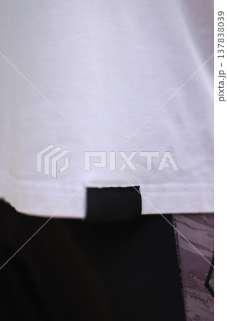 Closeup Of Garment Hem Contrast. Detailed View Of Tshirt Hem With Fabric Label And Contrast Waistband Closeup Of Garment Hem Contrast. Detailed View Of Tshirt Hem With Fabric Label And Contrast Waistband 137838039
