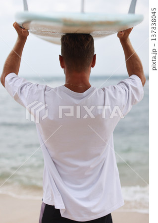 Surfer In Sunlit Coastal Environment. Beachside Man Preparing To Surf Against Sunlight Background Surfer In Sunlit Coastal Environment. Beachside Man Preparing To Surf Against Sunlight Background 137838045