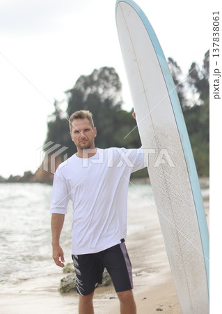Casual Model Posed Beside Surfboard By Ocean. Photograph Of Woman In T Shirt With Surfboard At Beach 137838061