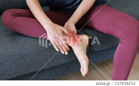 Woman massaging painful ankle and foot with red highlight. Ankle sprain, tendonitis, foot pain, gout and inflammation concept for health care, physical therapy and orthopedic medical treatment. Woman massaging painful ankle and foot with red highlight. Ankle sprain, tendonitis, foot pain, gout and inflammation concept for health care, physical therapy and orthopedic medical treatment. 137838252