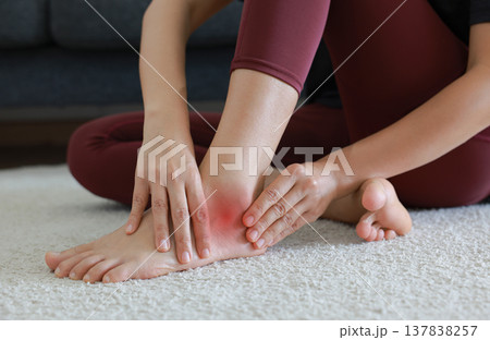 Woman massaging painful ankle and foot with red highlight. Ankle sprain, tendonitis, foot pain, gout and inflammation concept for health care, physical therapy and orthopedic medical treatment. Woman massaging painful ankle and foot with red highlight. Ankle sprain, tendonitis, foot pain, gout and inflammation concept for health care, physical therapy and orthopedic medical treatment. 137838257