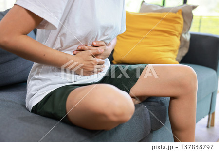 Woman holding her stomach with red highlight. Abdominal pain, liver disease, kidney pain, appendicitis and stomach ache concept for health care and medical treatment. Woman holding her stomach with red highlight. Abdominal pain, liver disease, kidney pain, appendicitis and stomach ache concept for health care and medical treatment. 137838797