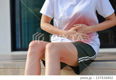 Woman holding her stomach with red highlight. Abdominal pain, liver disease, kidney pain, appendicitis and stomach ache concept for health care and medical treatment. 137838802