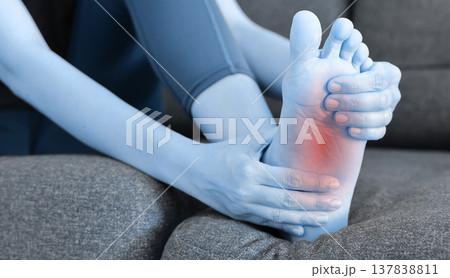 Asian woman standing and massaging her painful heel with red highlight. Heel spur, plantar fasciitis, Achilles tendonitis and foot injury concept for health care, physical therapy and medicine. 137838811