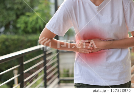 Woman holding her stomach with red highlight. Abdominal pain, liver disease, kidney pain, appendicitis and stomach ache concept for health care and medical treatment. Woman holding her stomach with red highlight. Abdominal pain, liver disease, kidney pain, appendicitis and stomach ache concept for health care and medical treatment. 137838970