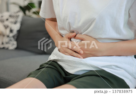 Woman holding her stomach with red highlight. Abdominal pain, liver disease, kidney pain, appendicitis and stomach ache concept for health care and medical treatment. Woman holding her stomach with red highlight. Abdominal pain, liver disease, kidney pain, appendicitis and stomach ache concept for health care and medical treatment. 137838975