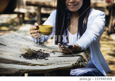 Woman drinking coffee hands holding hot disposable cup in green park. Happy Relax beautiful asian woman smiling face standing outdoors garden. Young women enjoy nature morning Freedom Lifestyle. Woman drinking coffee hands holding hot disposable cup in green park. Happy Relax beautiful asian woman smiling face standing outdoors garden. Young women enjoy nature morning Freedom Lifestyle. 137840309