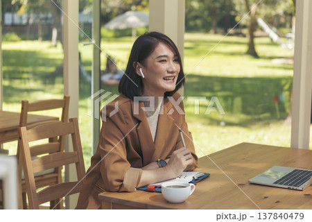 Happy asian woman video call web conference sitting on cozy sofa in living room at home. Smile Female asian people use laptop notebook computer headphones online call working from home watching video 137840479