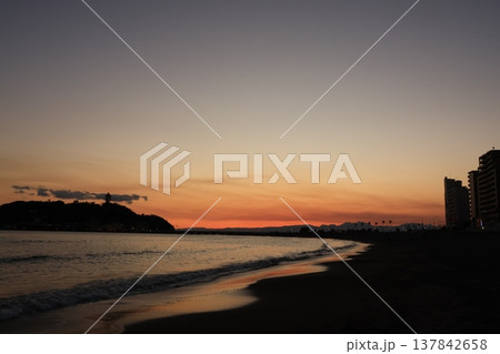日没時に腰越海岸から見るオレンジ色に染まる江ノ島付近の風景 137842658