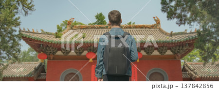 Young Man with Backpack Looking at Chinese Temple, Beijing 137842856