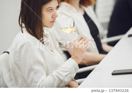 Close up portrait of professional female sommelier tasting white wine. 137843226