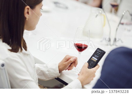 Portrait from the back of professional female sommelier looking red wine and analysis color, close up shot. Portrait from the back of professional female sommelier looking red wine and analysis color, close up shot. 137843228