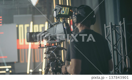 Professional cameraman filming breaking news in live TV studio with copy space Professional cameraman filming breaking news in live TV studio with copy space 137843901