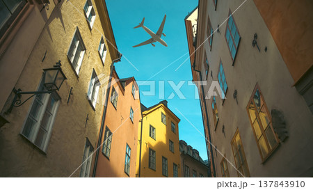 Airplane flying over colorful narrow street in Stockholm Gamla Stan with copy space 137843910