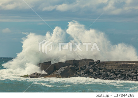 High Energy Ocean Wave Crashing Against Stone Pier with Huge Water Splash and Copy Space 137844269