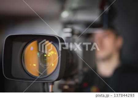 Professional broadcast camera lens in news studio with amber reflection and copy space 137844293