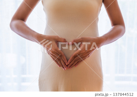 Pregnant woman makes a heart shape with her hands to symbolize love for baby. 137844512