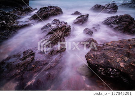 Beach rocks or stone with soft waves at sunset as a background. Beach rocks or stone with soft waves at sunset as a background. 137845291