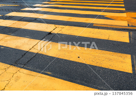 Crosswalk with yellow lines and shadow patterns on the ground during daytime Crosswalk with yellow lines and shadow patterns on the ground during daytime 137845356