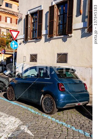 Car parks near building on narrow street during bright sunny day in city 137845383