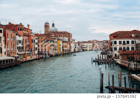 Canal flows through buildings in Venice under a cloudy sky in the afternoon light 137845392