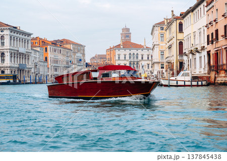 Boat travels through the waterways of Venice with historic buildings in the background Boat travels through the waterways of Venice with historic buildings in the background 137845438