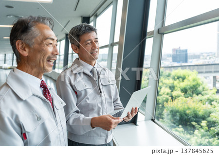 現場でパソコンを操作する作業服の男性 137845625