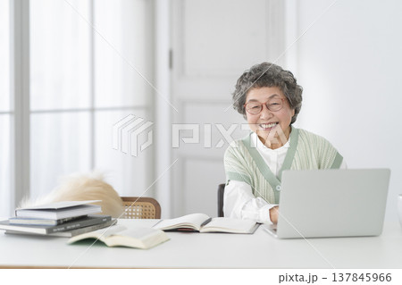 ノートパソコンで作業をする80代の女性 カメラ目線で笑顔のポートレート ノートパソコンで作業をする80代の女性 カメラ目線で笑顔のポートレート 137845966