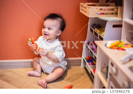 A cute little child smiles very happy while playing with toys made from wood and non-toxic paint to enhance their development. 137846278