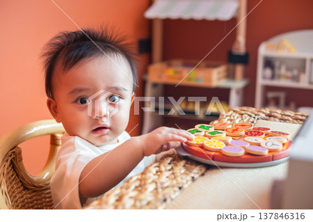 A cute little child smiles happily while playing with toys made from wood and non-toxic paint to enhance their development. 137846316