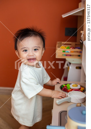 A cute little child smiles very happy while playing with toys made from wood and non-toxic paint to enhance their development. A cute little child smiles very happy while playing with toys made from wood and non-toxic paint to enhance their development. 137846317