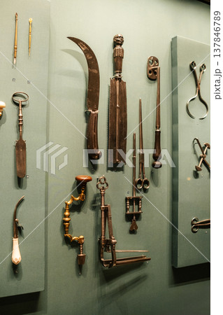 A variety of antique surgical tools arranged on a display board, highlighting the evolution of medical practices through intricate designs and craftsmanship. A variety of antique surgical tools arranged on a display board, highlighting the evolution of medical practices through intricate designs and craftsmanship. 137846789