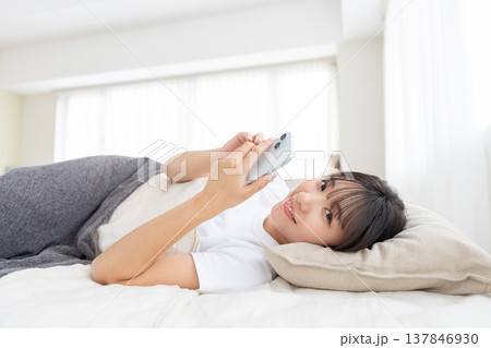 ベッドでスマホを操作する若い女性 ベッドでスマホを操作する若い女性 137846930