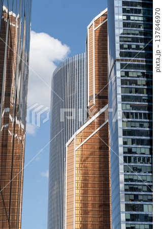 Skyscrapers in Moscow rise dramatically, their glass facades reflecting sunlight and clouds, highlighting the blend of modern design in the cityscape. 137846970