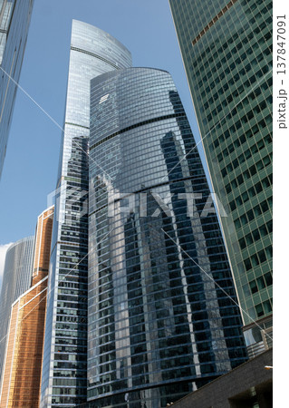 Tall skyscrapers showcase sleek glass facades that reflect each other and the blue sky, creating a vibrant atmosphere in Moscows bustling business district. 137847091
