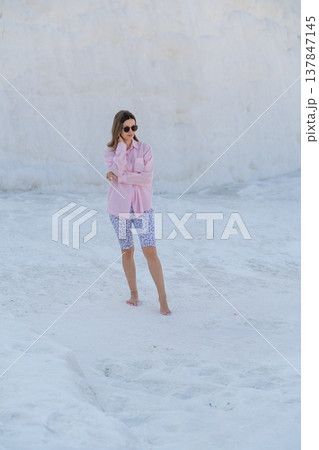A woman strolls barefoot on the travertine terraces of Pamukkale, taking in the warm thermal waters and the breathtaking white scenery on a sunny day A woman strolls barefoot on the travertine terraces of Pamukkale, taking in the warm thermal waters and the breathtaking white scenery on a sunny day 137847145