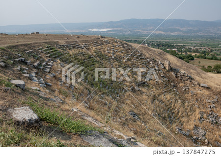 Exploring the ruins of Laodikeia, ancient town featuring remnants of a theater and scenic views of the surrounding mountains and fields. 137847275