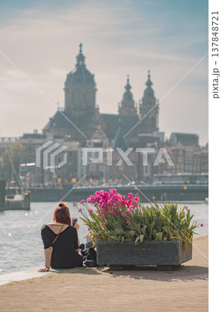 Young woman traveler admiring Basilica of Saint Nicholas and tulips in Amsterdam with copy space Young woman traveler admiring Basilica of Saint Nicholas and tulips in Amsterdam with copy space 137848721