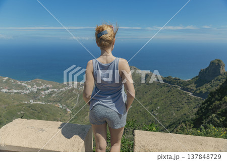 Young woman traveler enjoying breathtaking ocean and mountain view with copy space in sky Young woman traveler enjoying breathtaking ocean and mountain view with copy space in sky 137848729