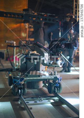 Professional Cinema Camera on Dolly Tracks During Production with Blue Lighting Professional Cinema Camera on Dolly Tracks During Production with Blue Lighting 137848786