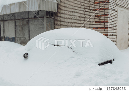 Parking of cars covered with snow. Heavy snowfall covered the road. Car in the snow. Consequences of a snowstorm.Abandoned car on the side of the road. 137848988
