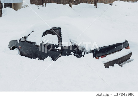 Parking of cars covered with snow. Heavy snowfall covered the road. Car in the snow. Consequences of a snowstorm.Abandoned car on the side of the road. 137848990