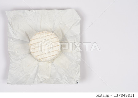 Small round blue cheese in opened paper wrapper 137849811