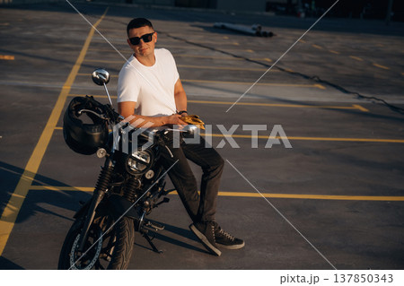 Standing and posing. Man is outdoors with his motorcycle Standing and posing. Man is outdoors with his motorcycle 137850343