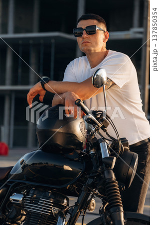 Standing and posing. Man is outdoors with his motorcycle 137850354