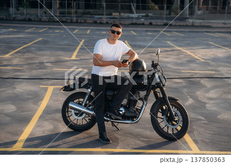 Smartphone is in hands. Man is outdoors with his motorcycle Smartphone is in hands. Man is outdoors with his motorcycle 137850363