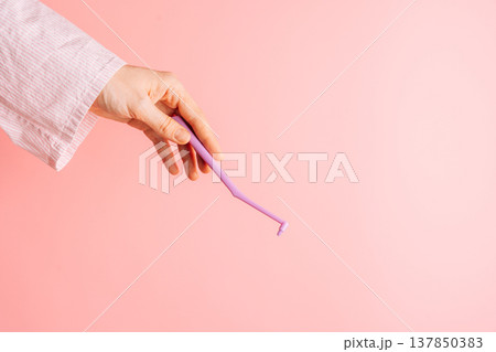Hand holding a single tuft toothbrush on pink background, minimal oral care concept with copy space 137850383