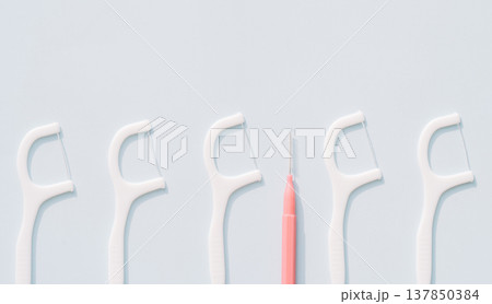 Dental floss picks lined up with an interdental brush, oral hygiene tools comparison on light blue background 137850384